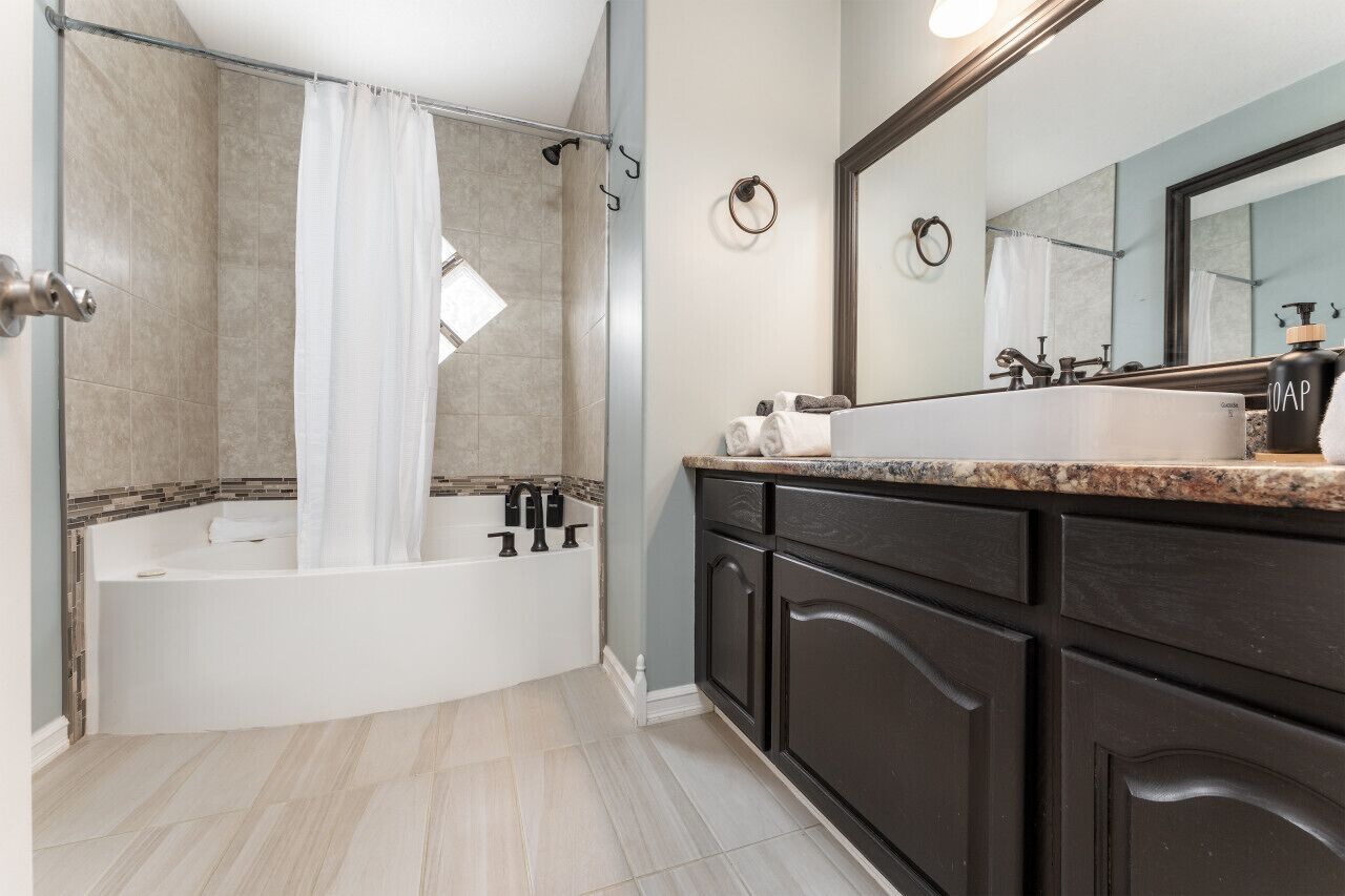 Une salle de bain moderne avec une baignoire sur pieds, des meubles de couleur sombre et un grand miroir.