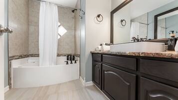 Une salle de bain moderne avec une baignoire sur pieds, des meubles de couleur sombre et un grand miroir.