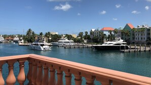 Un port de plaisance où sont amarrés plusieurs yachts, un pont orné de balustrades et, au loin, des bâtiments aux toits rouges.