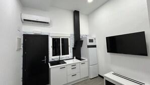 Cocina compacta con microondas, horno y televisor de pantalla plana montado en la pared.