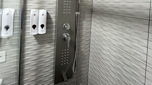 Una ducha moderna con panel de control, cabezal de ducha de mano y grifo empotrado.