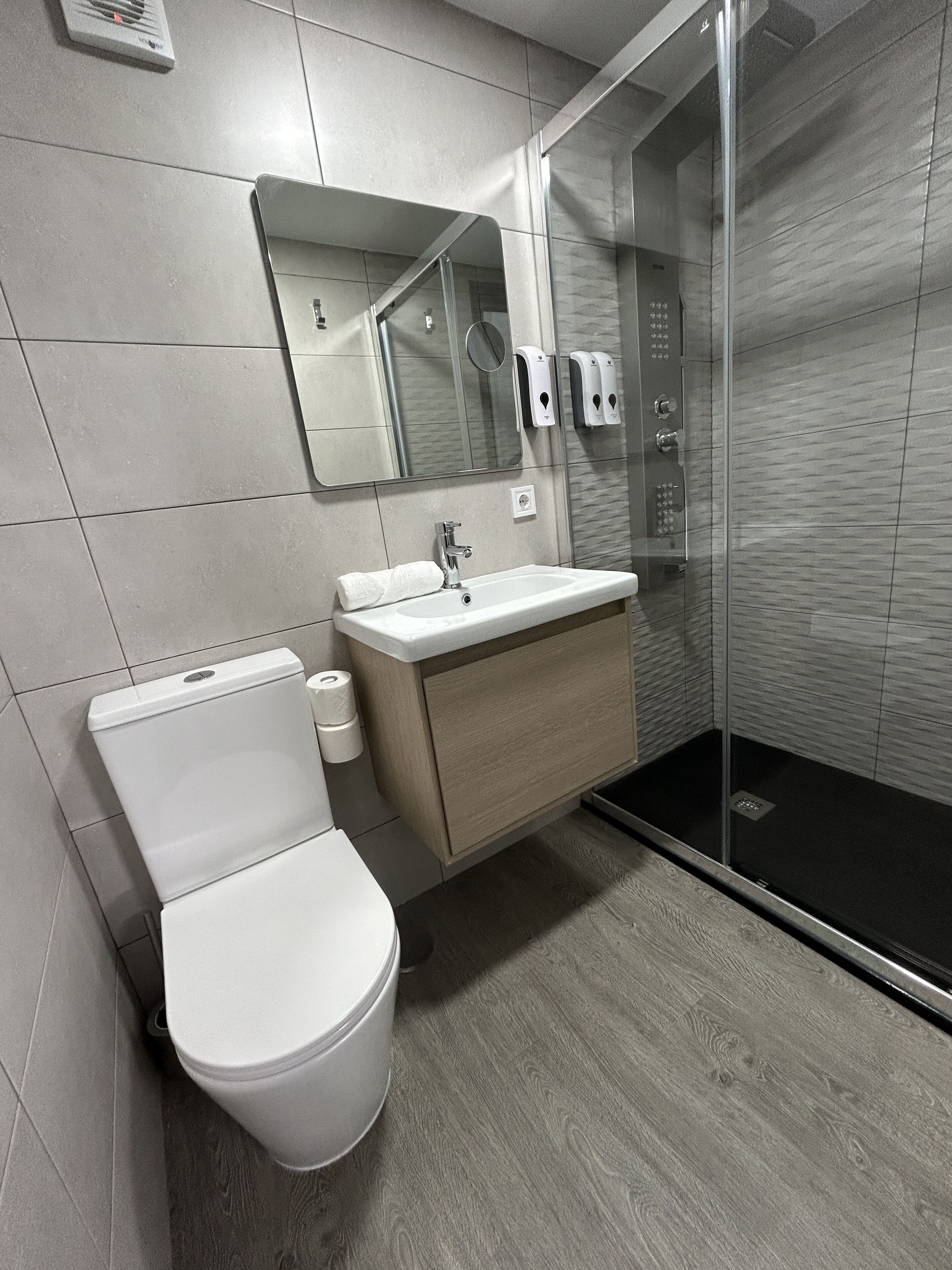 Un bagno moderno con WC, lavabo e cabina doccia in vetro.