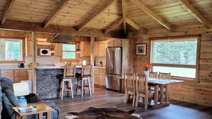 L’intérieur d’un chalet rustique comprend un coin repas, une cuisine et un espace salon.