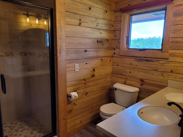 A wooden cabin bathroom with a shower, toilet, and sink. - 30 miles to East Entrance Yellowstone (Cody)