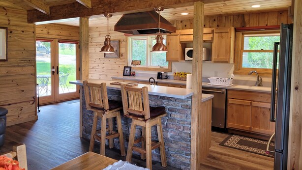 Une cuisine rustique avec des meubles en bois, un îlot central en pierre et des tabourets de bar.