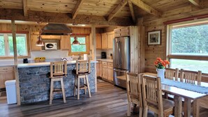Une cuisine rustique avec des meubles en bois, un îlot central en pierre et un grand réfrigérateur.
