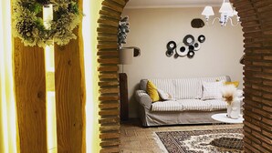 Un salon chaleureux avec une arche en briques, un poteau en bois et une guirlande décorative.