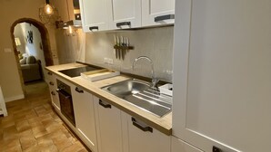 Une cuisine moderne avec des meubles blancs, un évier double et un sol à motifs en chevrons.