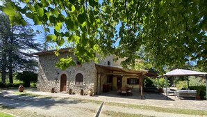 Un bâtiment en pierre doté d’un patio, d’un espace extérieur aménagé avec des sièges et d’une pergola.