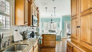 A kitchen with wooden cabinets, granite countertops, stainless steel appliances, and a large window. - Ocean Lakes Site MH191A with Lake View, 4-bedroom 3-bath with loft. Sleeps 10 (Myrtle Beach)