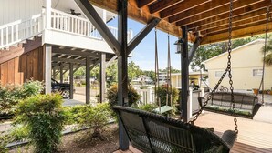 A covered outdoor area with a swing set, wooden deck, and a view of a residential neighborhood. - Ocean Lakes Site MH191A with Lake View, 4-bedroom 3-bath with loft. Sleeps 10 (Myrtle Beach)