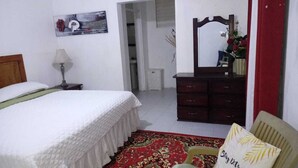 A bedroom with a bed, a dresser, a mirror, and a chair. - HABITACION A 5 MINUTOS DEL AEROPUERTO (Boca Chica)