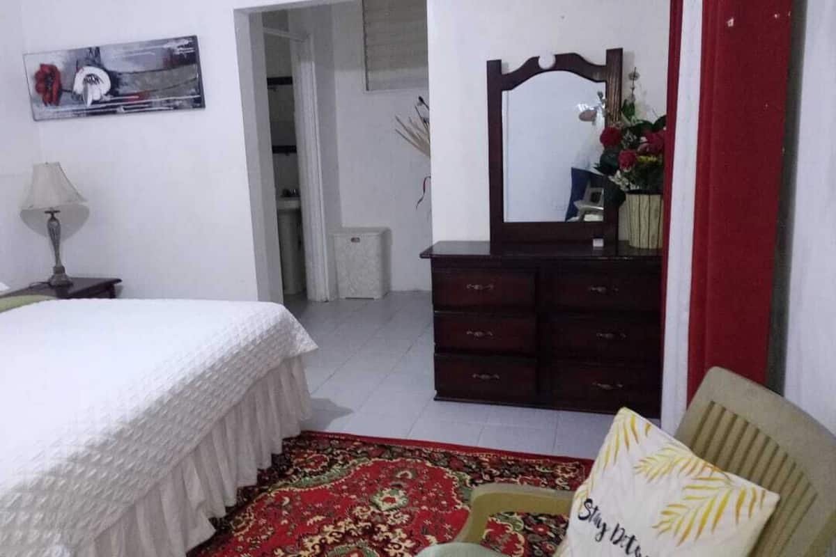Une chambre à coucher avec un lit, une commode, un miroir et une chaise.