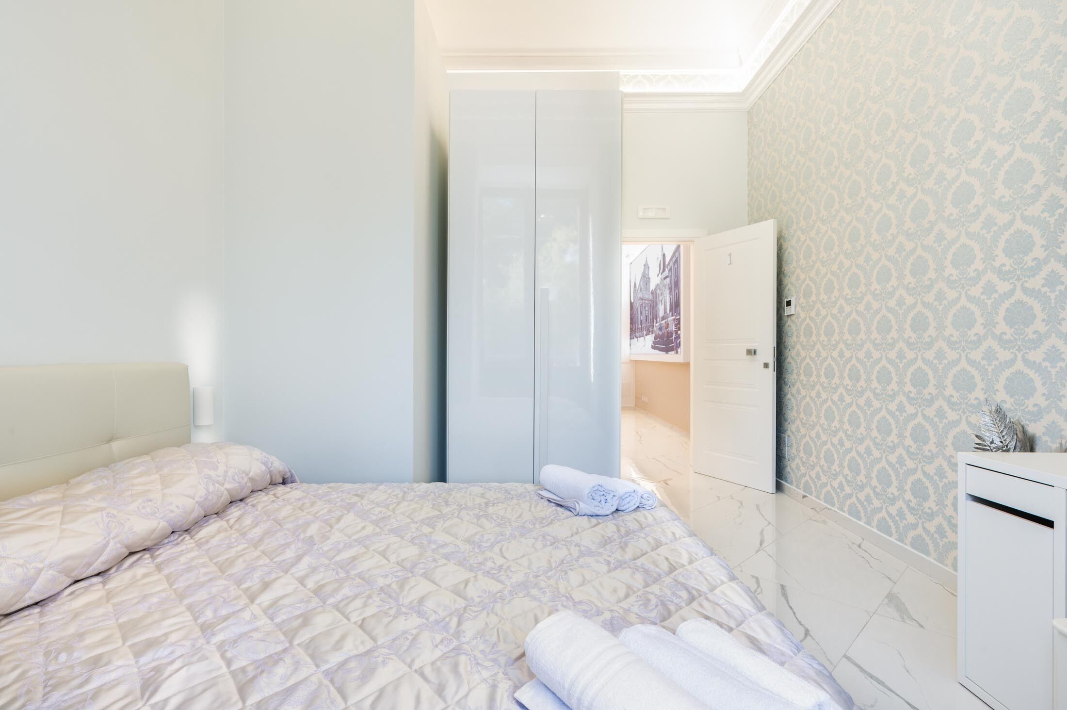 Une chambre à coucher avec un lit, une armoire et une porte donnant sur la salle de bain.