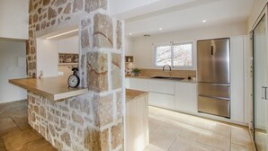Une cuisine moderne avec un élément décoratif en pierre, des appareils électroménagers en acier inoxydable et une grande fenêtre.