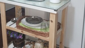 Un área de cocina con cafetera, hervidor y tostadora sobre una mesa de vidrio.