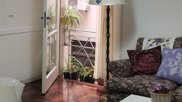 Una sala de estar con un sofá, una mesa, una lámpara y vistas al exterior.