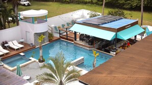 Zona de piscina en la azotea con bar, área de descanso e instalación de paneles solares.