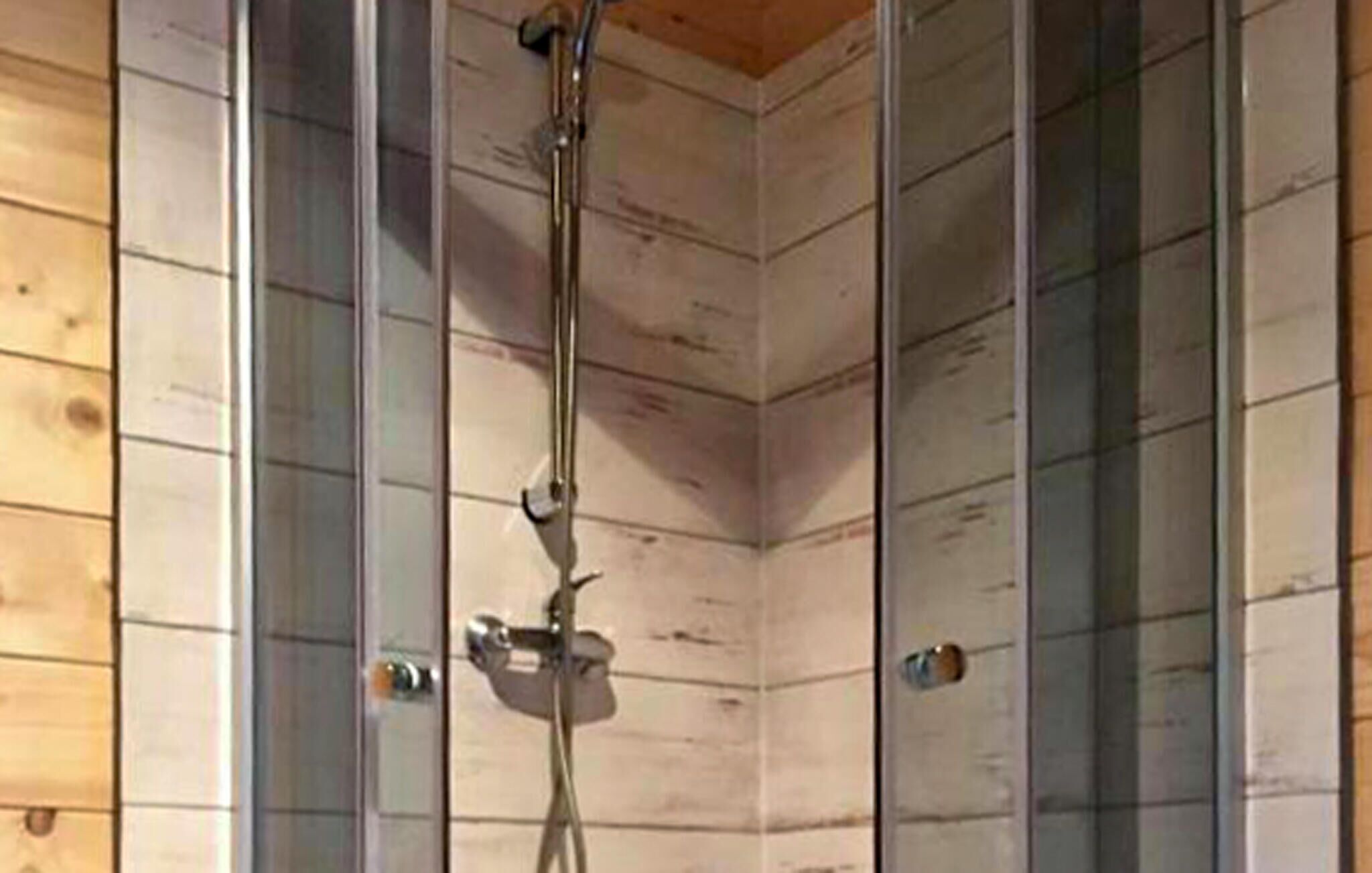 Un coin de pièce avec un lambris en bois et un espace douche.