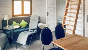 A cozy room with a sofa, two chairs, a small table, a lamp, and a wooden ladder.