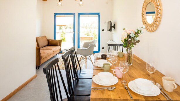 A dining area with a wooden table set for four, a brown sofa, and a chair. - Beautiful home in Rowy with house a panoramic view (Rowy)
