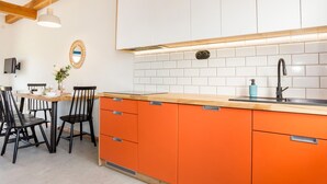 A modern kitchen with orange cabinets, a wooden ceiling, and white subway tiles. - Beautiful home in Rowy with house a panoramic view (Rowy)
