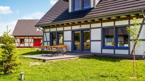 A modern house with a large porch, a bench, and a small garden. - Beautiful home in Rowy with house a panoramic view (Rowy)