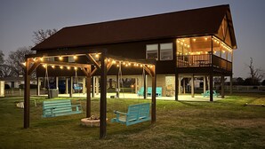 A two-story building with a covered patio area, benches, and string lights.