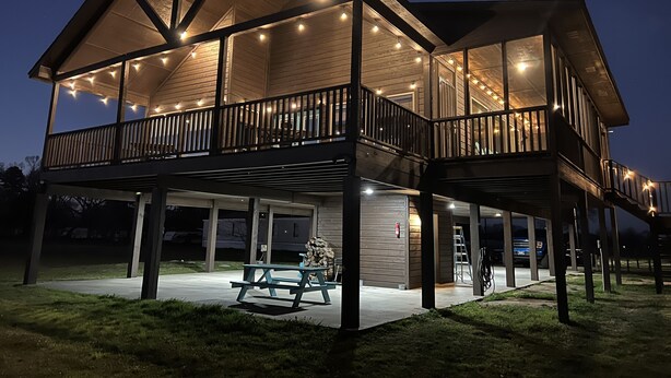 A two-story building with a covered patio area, outdoor seating, and string lights.