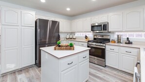 Una cocina moderna con armarios blancos, electrodomésticos de acero inoxidable y una isla central decorada.