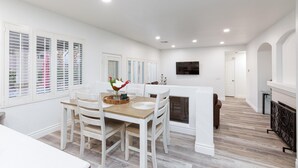 Un área de comedor con una mesa, sillas, chimenea y televisor montado en la pared.