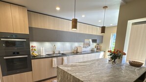Une cuisine moderne avec des meubles en bois, un îlot en marbre et des luminaires suspendus.