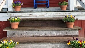 En træterrasse med en blå stol, trapper og blomsterkrukker.