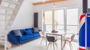 A modern living space with a blue sofa, a dining table with chairs, and a staircase. - Beautiful home in Taszów with sauna (Taszów)