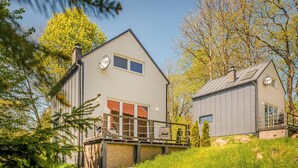 A modern two-story house with a balcony, surrounded by lush greenery and trees. - Beautiful home in Taszów with sauna (Taszów)