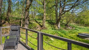A wooden deck with a metal railing overlooking a grassy area with trees. - Beautiful home in Taszów with sauna (Taszów)