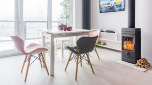 A modern living room with a white table, two chairs, a black fireplace, and a TV on the wall. - Beautiful home in Taszów with sauna (Taszów)