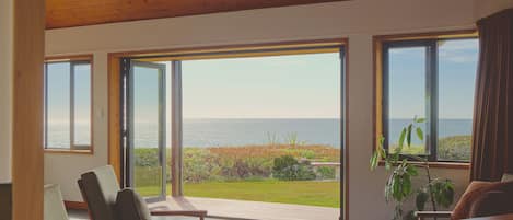 Una habitación con ventanas amplias, techo de madera y vista al mar.