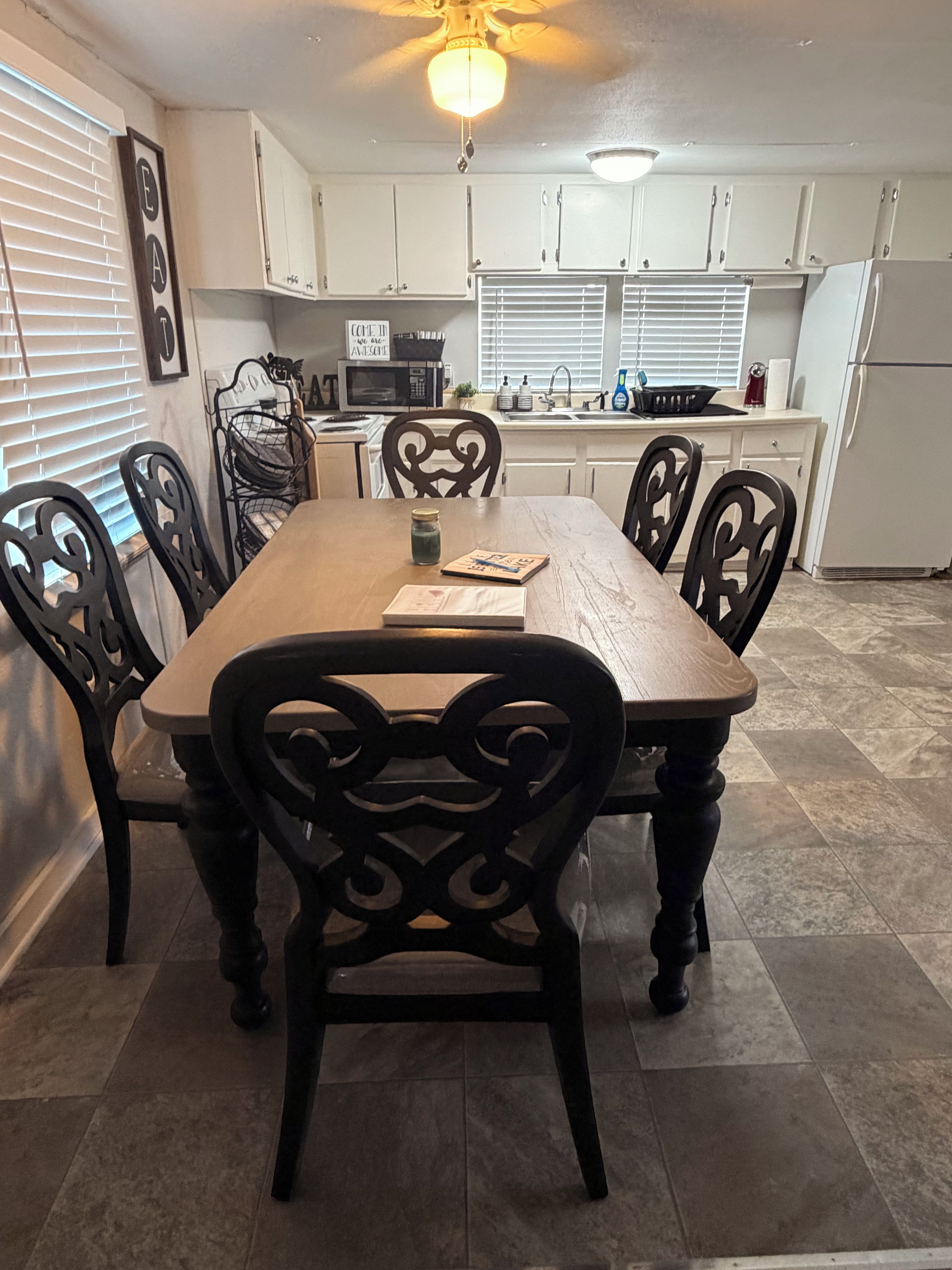 A dining area with a wooden table, black chairs, and a ceiling fan.