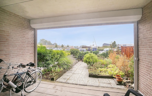Un balcon avec un vélo, un chemin de gravier et une vue sur un parking et des immeubles.