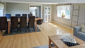 A spacious living area with a dining table and chairs, a sofa, and a window with a view.