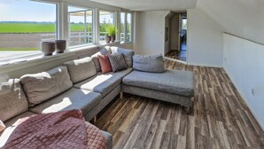 A modern living room with a sectional sofa, a view of a green field, and a wooden floor.