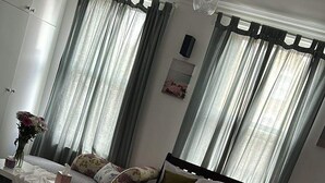 A modern bedroom with a large bed, a bedside table, a chair, and a window with curtains. - STUDIO FLAT IN ACTION  (London)