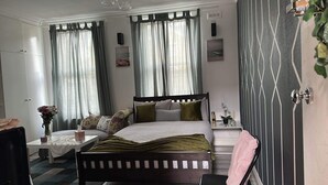 A bedroom with a bed, bedside tables, a chair, a desk, and curtains. - STUDIO FLAT IN ACTION  (London)