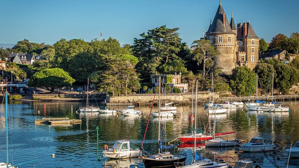Een haven met boten, een kasteel en omliggende begroeiing.