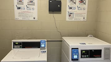 Two commercial washers and dryers, labeled 'Speed Queen', with instructional posters on the wall.