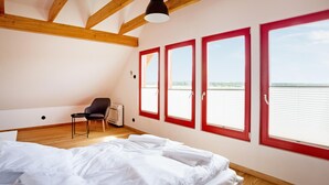 Een slaapkamer met een bed, een stoel en een raam met uitzicht op het water.