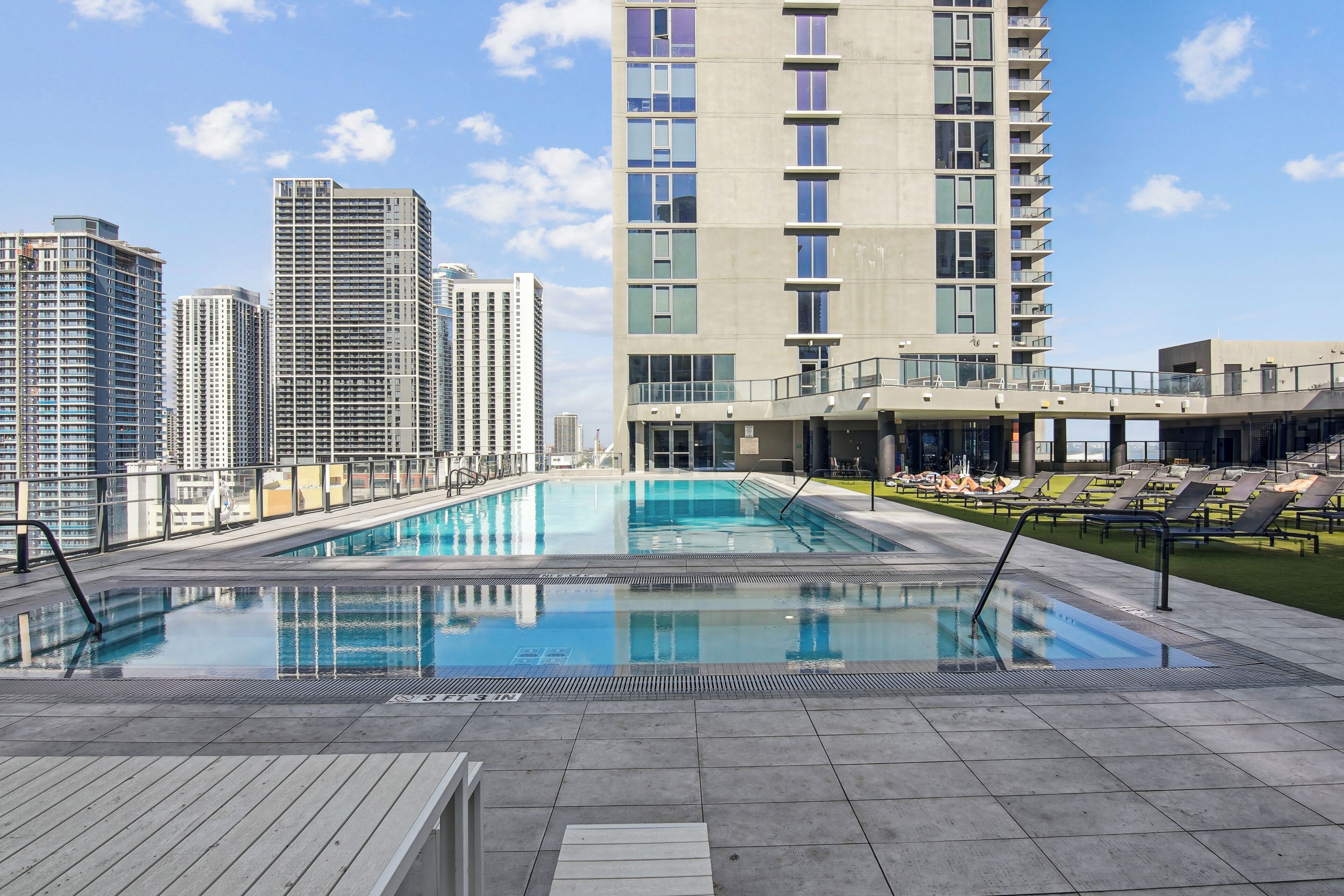Una piscina en la azotea con vista a la ciudad, rodeada de rascacielos.
