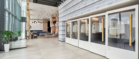 A modern interior with a high ceiling, geometric lighting, and a mix of open and enclosed spaces.