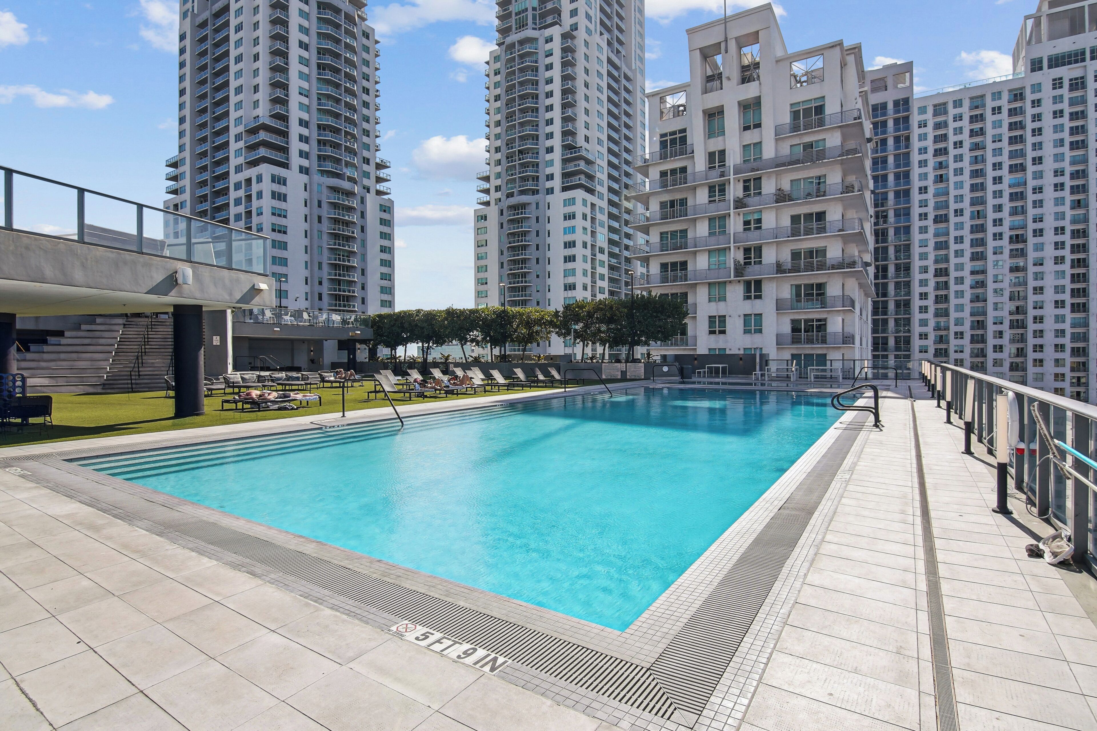 A swimming pool with a tiled deck, surrounded by high-rise residential buildings.